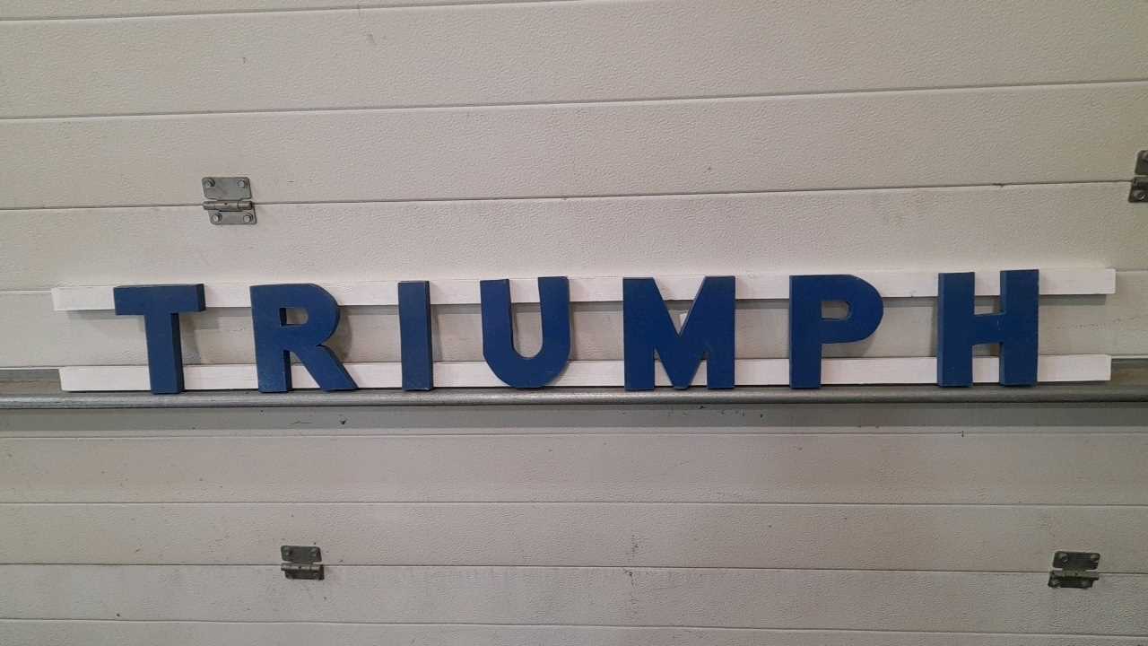 Lot 22 - WOODEN HAND PAINTED TRIUMPH LETTERS 57" X 6"