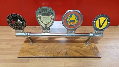 Lot 565 - 4 VINTAGE CAR BADGES ON LIGHT WOODEN BASE