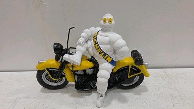 Lot 261 - PLASTIC MICHELIN MAN ON YELLOW BIKE 18" X 13"
